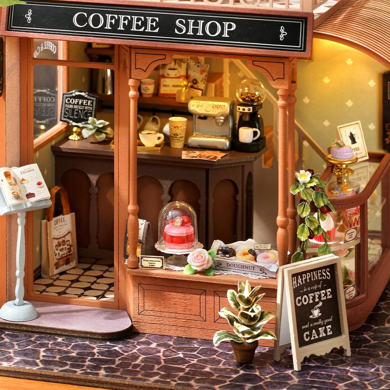 DIY mini house kit “Perch & Latte Loft,” featuring a cozy two-story coffee shop with a glowing café interior, reading nook, lace-curtained loft, and tiny desserts. A warm and detailed build for DIY and crafts lovers and fans of miniature homes.