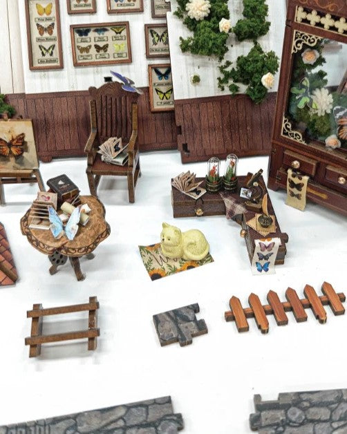 DIY book nook kit “Butterfly Cottage,” featuring a beautiful nature-themed miniature with butterflies, rocking chair, wooden signs, and blooming flowers. A peaceful DIY and crafts project perfect for miniature lovers.
