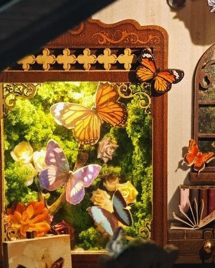 DIY book nook kit “Butterfly Cottage,” featuring a beautiful nature-themed miniature with butterflies, rocking chair, wooden signs, and blooming flowers. A peaceful DIY and crafts project perfect for miniature lovers.