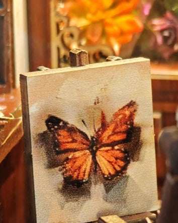 DIY book nook kit “Butterfly Cottage,” featuring a beautiful nature-themed miniature with butterflies, rocking chair, wooden signs, and blooming flowers. A peaceful DIY and crafts project perfect for miniature lovers.