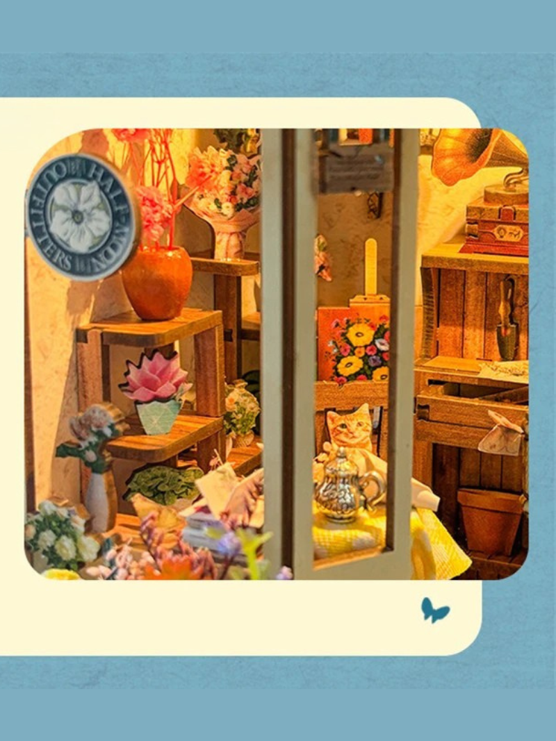 DIY book nook kit “Springkeeper’s Shop” featuring a cheerful miniature flower store with potted plants, blooming flowers, a striped awning, and a small cat. A charming craft idea for DIY and crafts lovers, perfect for fans of miniatures and DIY tiny home kits.