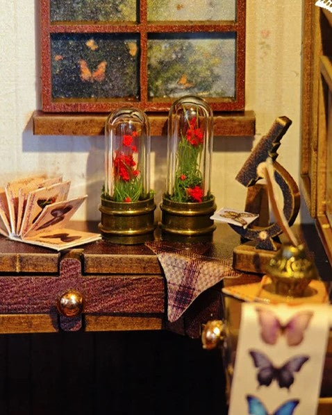 DIY book nook kit “Butterfly Cottage,” featuring a beautiful nature-themed miniature with butterflies, rocking chair, wooden signs, and blooming flowers. A peaceful DIY and crafts project perfect for miniature lovers.