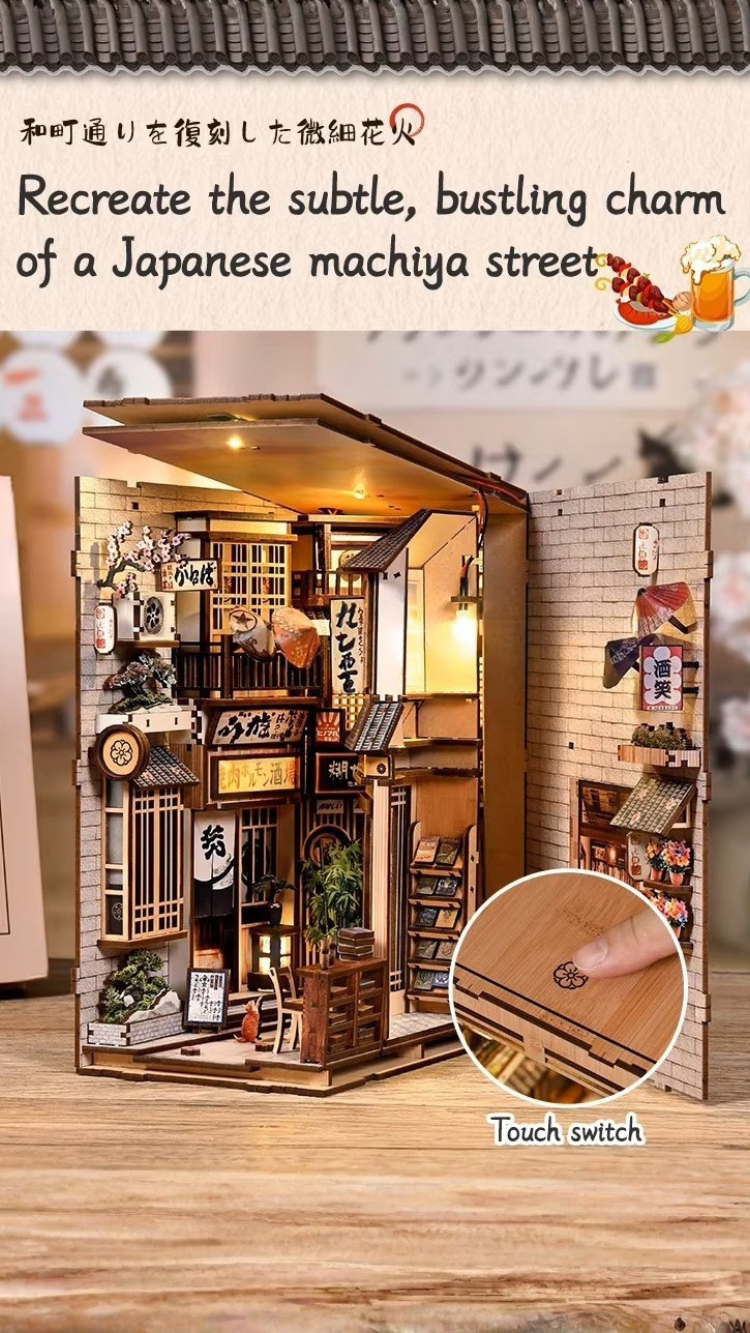 DIY book nook kit “Neko Alley Nook,” featuring a Japanese alleyway with miniature shopfronts, paper lanterns, wooden signage, and lounging cats. A charming DIY and crafts project for Japan enthusiasts and book nook collectors.