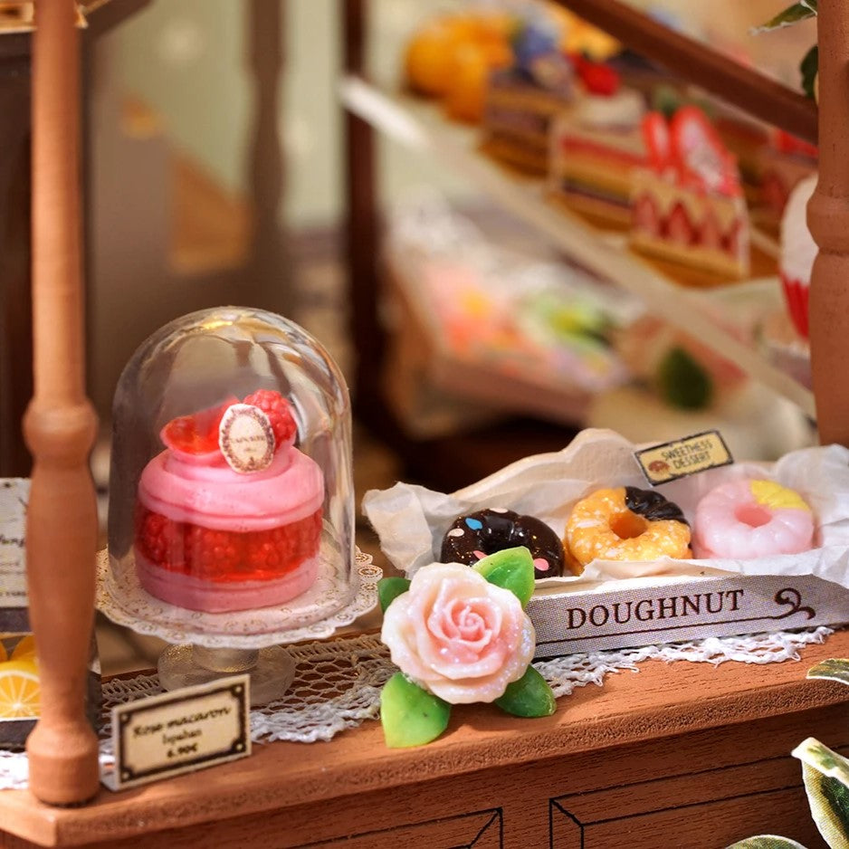 DIY mini house kit “Perch & Latte Loft,” featuring a cozy two-story coffee shop with a glowing café interior, reading nook, lace-curtained loft, and tiny desserts. A warm and detailed build for DIY and crafts lovers and fans of miniature homes.