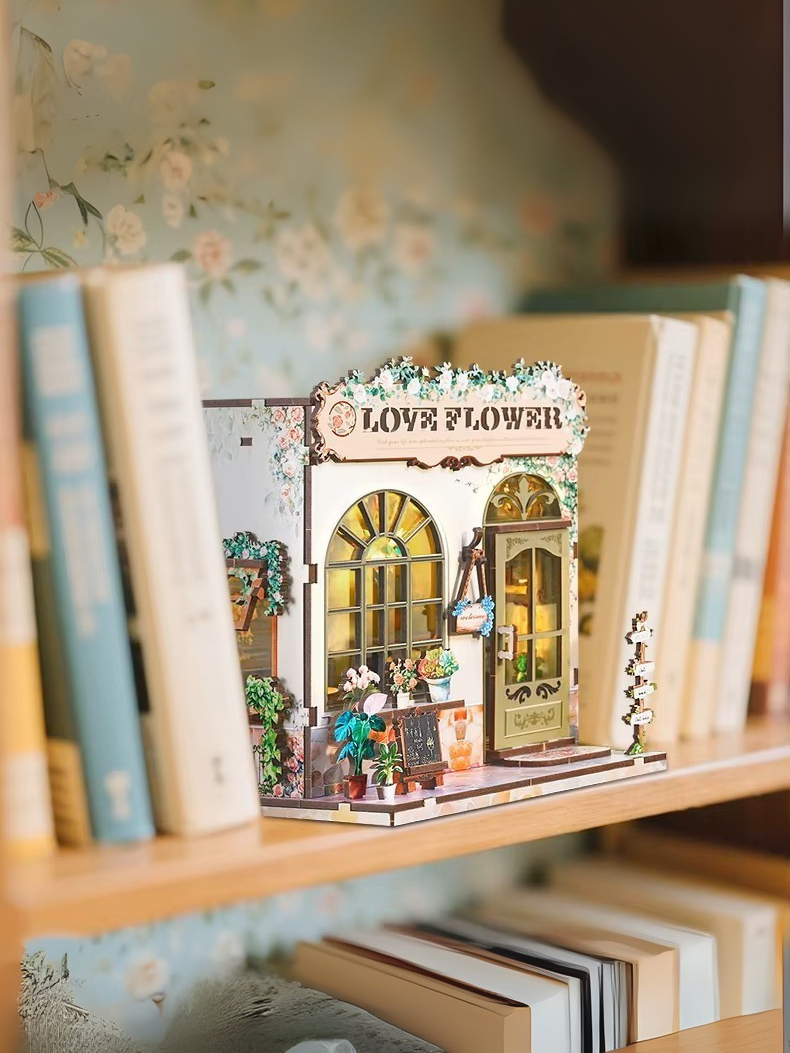 DIY book nook kit “Maison de Fleurs,” featuring a pastel-toned miniature flower shop with arched windows, blooming plants, stone accents, and romantic signage. A relaxing DIY and crafts project for fans of tiny dollhouses and garden-inspired scenes.