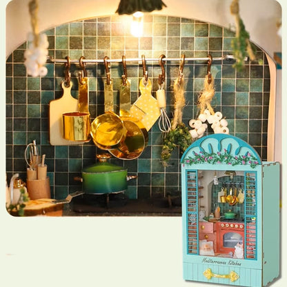 DIY book nook miniature kitchen with Mediterranean tiles, hanging copper pots, red oven, and open blue shutters.
