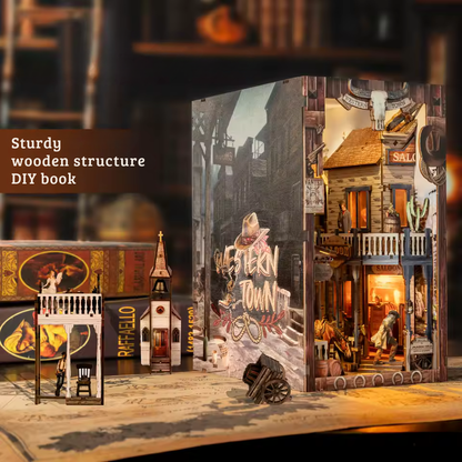 DIY miniature book nook of a Wild West street scene featuring a saloon façade with swinging doors, wooden signage, warm lantern lighting, and rustic storefront details, evoking a classic frontier town at dusk.