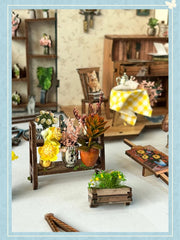 DIY book nook kit “Springkeeper’s Shop” featuring a cheerful miniature flower store with potted plants, blooming flowers, a striped awning, and a small cat. A charming craft idea for DIY and crafts lovers, perfect for fans of miniatures and DIY tiny home kits.