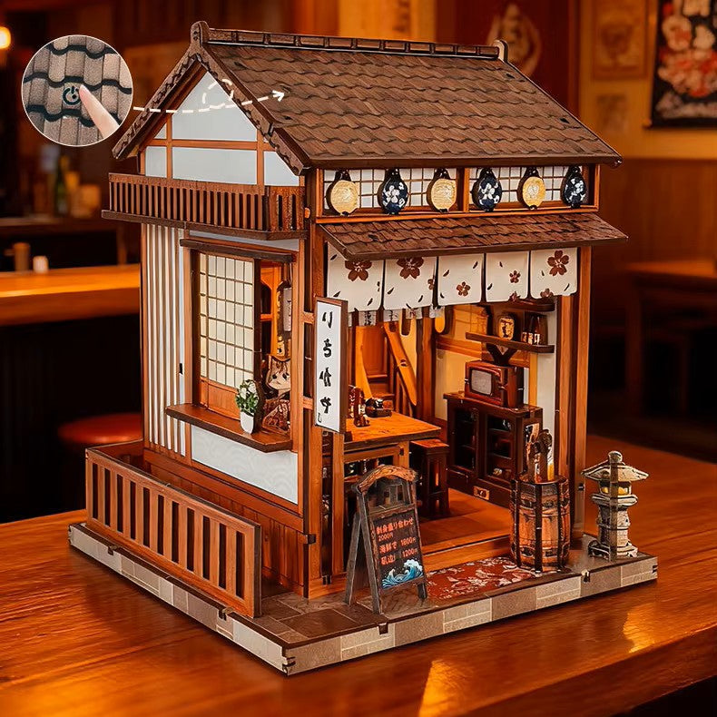 DIY miniature sake bar book nook with glowing lanterns, wooden bar seating, bamboo paneling, and rows of sake bottles, capturing the quiet atmosphere of a late-night Japanese tavern.