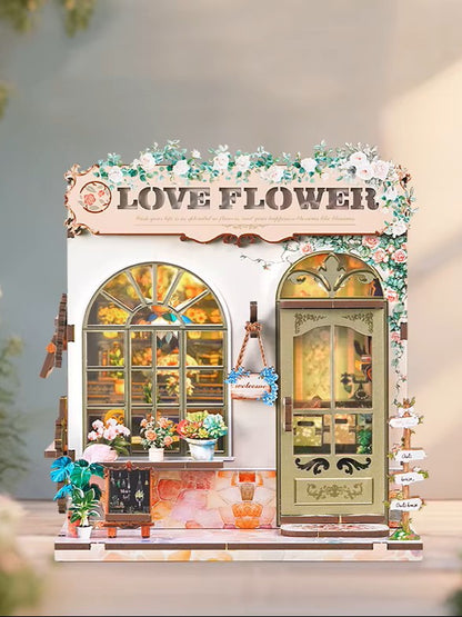 DIY book nook kit “Maison de Fleurs,” featuring a pastel-toned miniature flower shop with arched windows, blooming plants, stone accents, and romantic signage. A relaxing DIY and crafts project for fans of tiny dollhouses and garden-inspired scenes.
