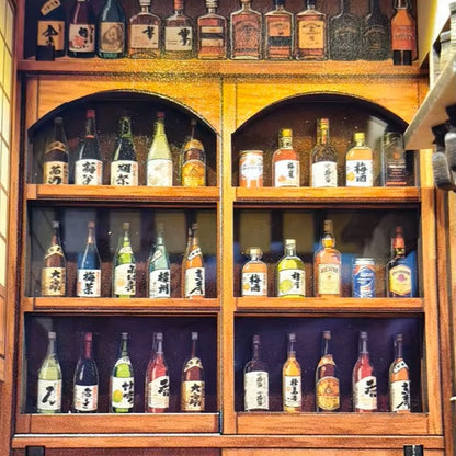 DIY miniature sake bar book nook with glowing lanterns, wooden bar seating, bamboo paneling, and rows of sake bottles, capturing the quiet atmosphere of a late-night Japanese tavern.