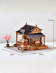 DIY mini house kit “Little Bao Shop,” featuring a traditional Chinese dumpling stand with miniature steamed buns, wooden tables, hanging signs, and a cherry blossom tree—perfect for DIY food miniatures and cultural craft ideas.