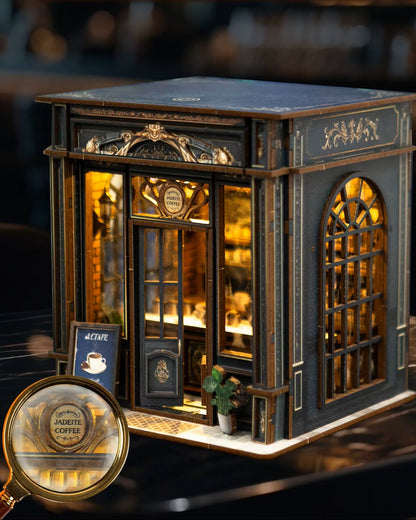 Miniature DIY book nook of a dark vintage-style café with glowing warm lights, ornate black storefront, and a coffee sign that reads “Jadeite Coffee.”