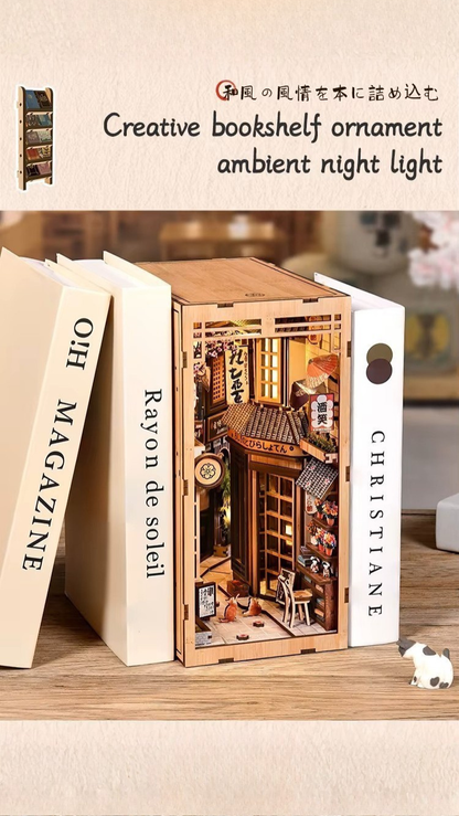 DIY book nook kit “Neko Alley Nook,” featuring a Japanese alleyway with miniature shopfronts, paper lanterns, wooden signage, and lounging cats. A charming DIY and crafts project for Japan enthusiasts and book nook collectors.