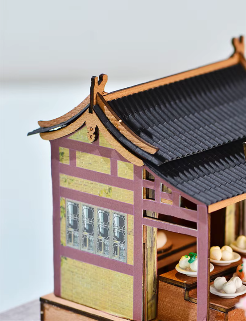 DIY mini house kit “Little Bao Shop,” featuring a traditional Chinese dumpling stand with miniature steamed buns, wooden tables, hanging signs, and a cherry blossom tree—perfect for DIY food miniatures and cultural craft ideas.
