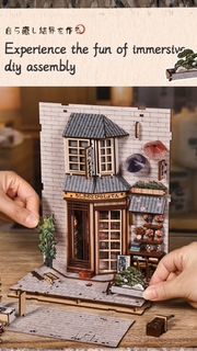 DIY book nook kit “Neko Alley Nook,” featuring a Japanese alleyway with miniature shopfronts, paper lanterns, wooden signage, and lounging cats. A charming DIY and crafts project for Japan enthusiasts and book nook collectors.