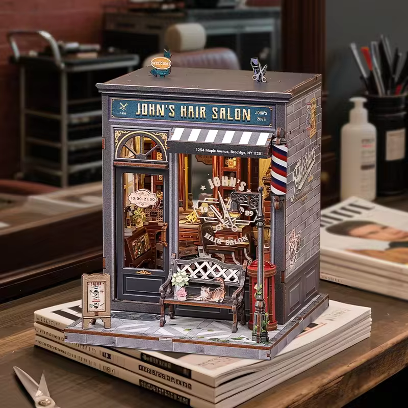 DIY book nook kit “Pomade Parlor,” featuring a vintage barbershop and hair salon interior with red chairs, mirrors, wooden shelves, and miniature grooming tools. A nostalgic DIY and crafts project for fans of retro style, miniatures, and classic salon design.
