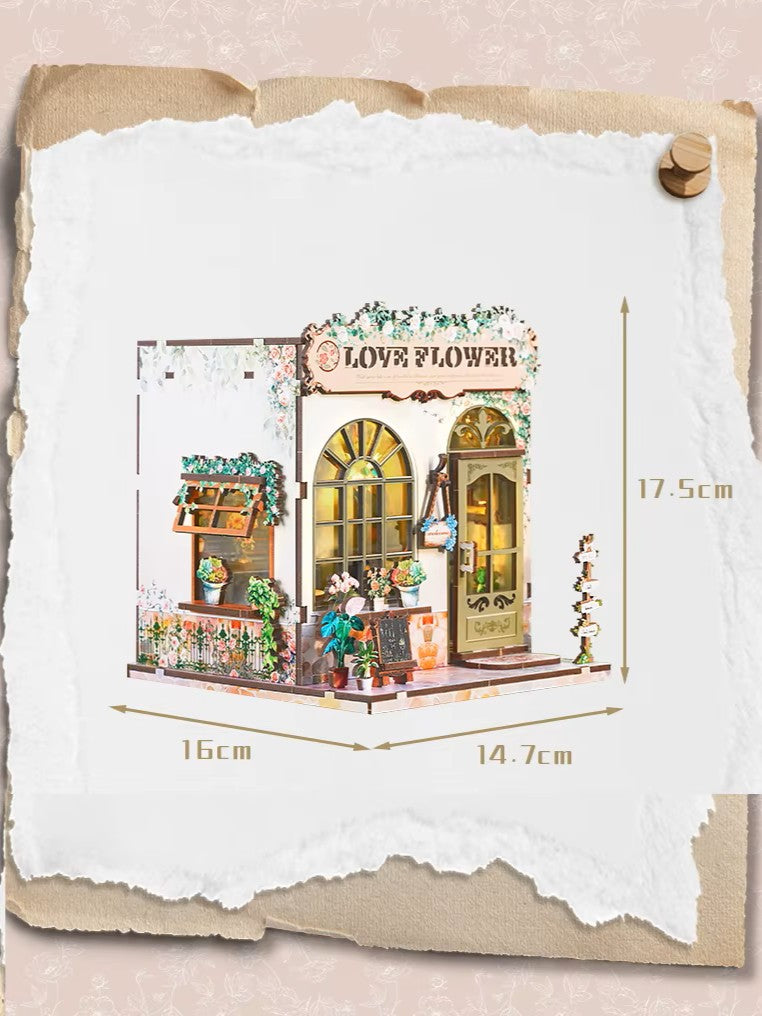 DIY book nook kit “Maison de Fleurs,” featuring a pastel-toned miniature flower shop with arched windows, blooming plants, stone accents, and romantic signage. A relaxing DIY and crafts project for fans of tiny dollhouses and garden-inspired scenes.