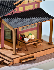 DIY mini house kit “Little Bao Shop,” featuring a traditional Chinese dumpling stand with miniature steamed buns, wooden tables, hanging signs, and a cherry blossom tree—perfect for DIY food miniatures and cultural craft ideas.