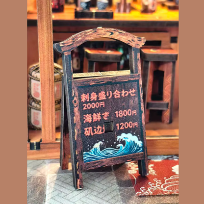 DIY miniature sake bar book nook with glowing lanterns, wooden bar seating, bamboo paneling, and rows of sake bottles, capturing the quiet atmosphere of a late-night Japanese tavern.