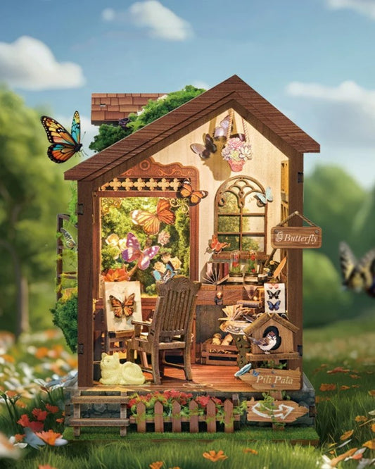 DIY book nook kit “Butterfly Cottage,” featuring a beautiful nature-themed miniature with butterflies, rocking chair, wooden signs, and blooming flowers. A peaceful DIY and crafts project perfect for miniature lovers.