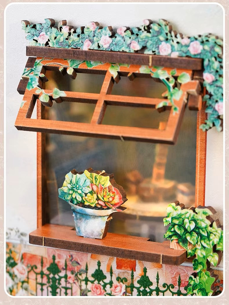 DIY book nook kit “Maison de Fleurs,” featuring a pastel-toned miniature flower shop with arched windows, blooming plants, stone accents, and romantic signage. A relaxing DIY and crafts project for fans of tiny dollhouses and garden-inspired scenes.