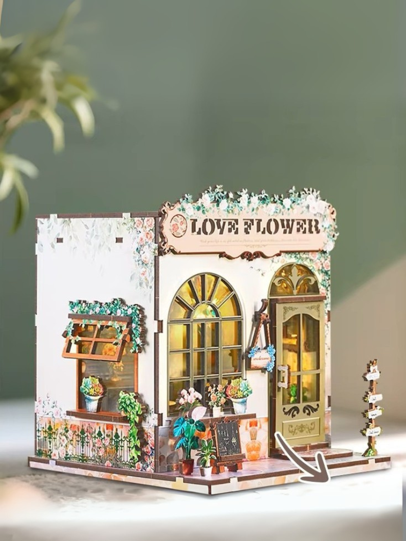 DIY book nook kit “Maison de Fleurs,” featuring a pastel-toned miniature flower shop with arched windows, blooming plants, stone accents, and romantic signage. A relaxing DIY and crafts project for fans of tiny dollhouses and garden-inspired scenes.
