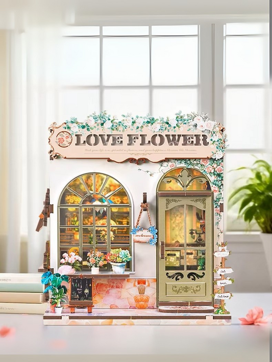 DIY book nook kit “Maison de Fleurs,” featuring a pastel-toned miniature flower shop with arched windows, blooming plants, stone accents, and romantic signage. A relaxing DIY and crafts project for fans of tiny dollhouses and garden-inspired scenes.