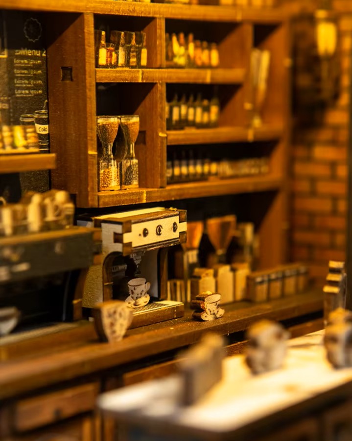 Miniature DIY book nook of a dark vintage-style café with glowing warm lights, ornate black storefront, and a coffee sign that reads “Jadeite Coffee.”
