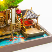 DIY miniature kit “Blossom Lantern Pavilion,” featuring a traditional East Asian-style building with curved roofs, cherry blossom trees, red lanterns, a waterfall, and glowing lights. A serene DIY and crafts project for fans of miniature homes and nature-inspired design.
