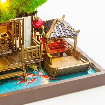 DIY miniature kit “Blossom Lantern Pavilion,” featuring a traditional East Asian-style building with curved roofs, cherry blossom trees, red lanterns, a waterfall, and glowing lights. A serene DIY and crafts project for fans of miniature homes and nature-inspired design.