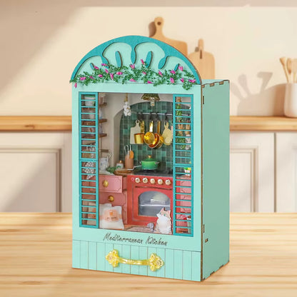 DIY book nook miniature kitchen with Mediterranean tiles, hanging copper pots, red oven, and open blue shutters.