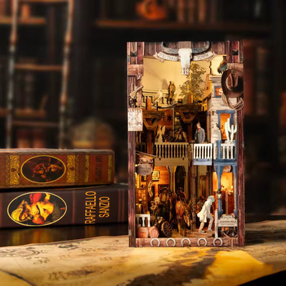 DIY miniature book nook of a Wild West street scene featuring a saloon façade with swinging doors, wooden signage, warm lantern lighting, and rustic storefront details, evoking a classic frontier town at dusk.