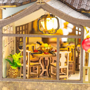 DIY miniature kit “Blossom Lantern Pavilion,” featuring a traditional East Asian-style building with curved roofs, cherry blossom trees, red lanterns, a waterfall, and glowing lights. A serene DIY and crafts project for fans of miniature homes and nature-inspired design.