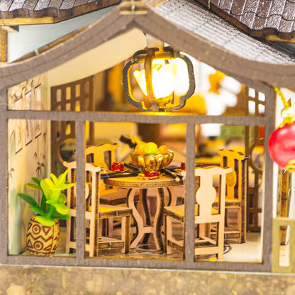 DIY miniature kit “Blossom Lantern Pavilion,” featuring a traditional East Asian-style building with curved roofs, cherry blossom trees, red lanterns, a waterfall, and glowing lights. A serene DIY and crafts project for fans of miniature homes and nature-inspired design.