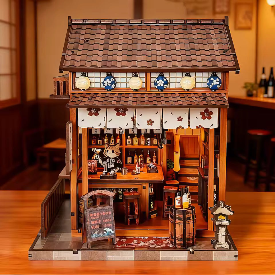 DIY miniature sake bar book nook with glowing lanterns, wooden bar seating, bamboo paneling, and rows of sake bottles, capturing the quiet atmosphere of a late-night Japanese tavern.