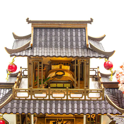 DIY miniature kit “Blossom Lantern Pavilion,” featuring a traditional East Asian-style building with curved roofs, cherry blossom trees, red lanterns, a waterfall, and glowing lights. A serene DIY and crafts project for fans of miniature homes and nature-inspired design.