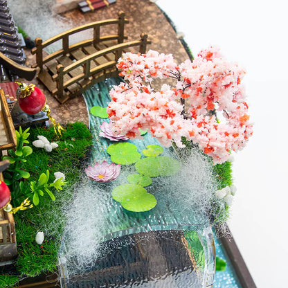 DIY miniature kit “Blossom Lantern Pavilion,” featuring a traditional East Asian-style building with curved roofs, cherry blossom trees, red lanterns, a waterfall, and glowing lights. A serene DIY and crafts project for fans of miniature homes and nature-inspired design.