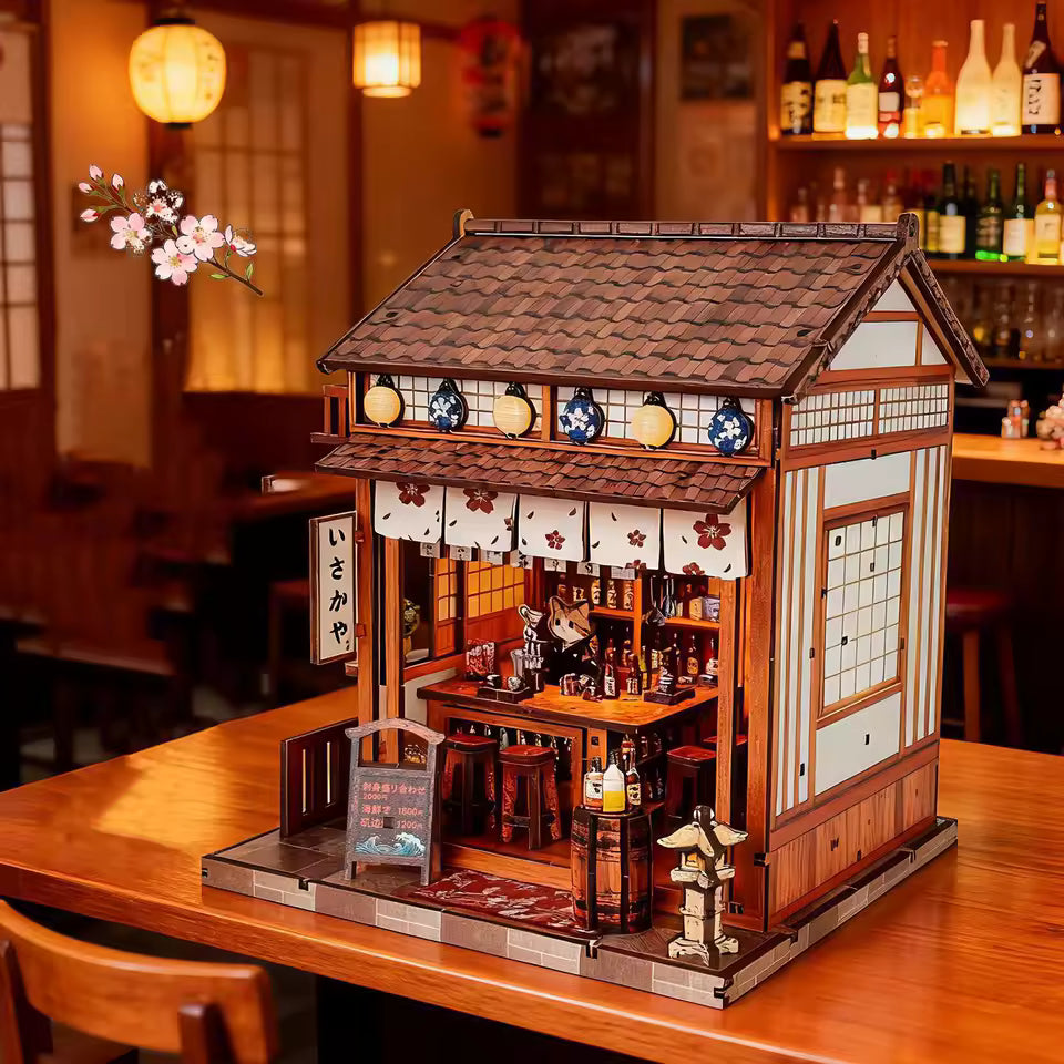 DIY miniature sake bar book nook with glowing lanterns, wooden bar seating, bamboo paneling, and rows of sake bottles, capturing the quiet atmosphere of a late-night Japanese tavern.