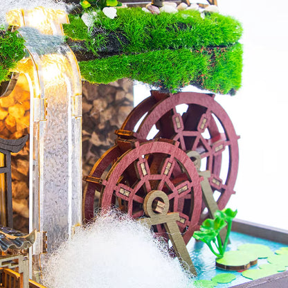 DIY miniature kit “Blossom Lantern Pavilion,” featuring a traditional East Asian-style building with curved roofs, cherry blossom trees, red lanterns, a waterfall, and glowing lights. A serene DIY and crafts project for fans of miniature homes and nature-inspired design.