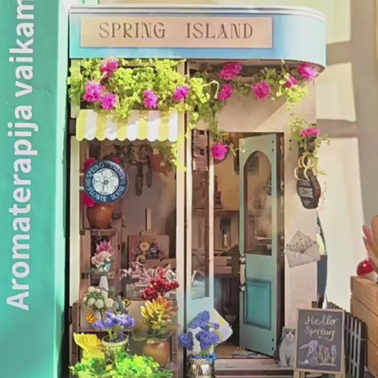DIY book nook kit “Springkeeper’s Shop” featuring a cheerful miniature flower store with potted plants, blooming flowers, a striped awning, and a small cat. A charming craft idea for DIY and crafts lovers, perfect for fans of miniatures and DIY tiny home kits.