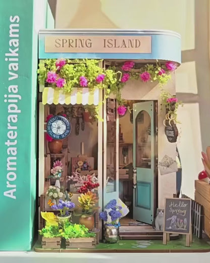 DIY book nook kit “Springkeeper’s Shop” featuring a cheerful miniature flower store with potted plants, blooming flowers, a striped awning, and a small cat. A charming craft idea for DIY and crafts lovers, perfect for fans of miniatures and DIY tiny home kits.