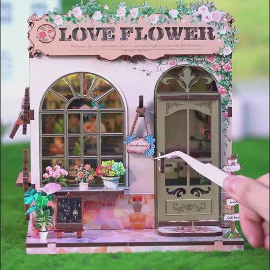 DIY book nook kit “Maison de Fleurs,” featuring a pastel-toned miniature flower shop with arched windows, blooming plants, stone accents, and romantic signage. A relaxing DIY and crafts project for fans of tiny dollhouses and garden-inspired scenes.