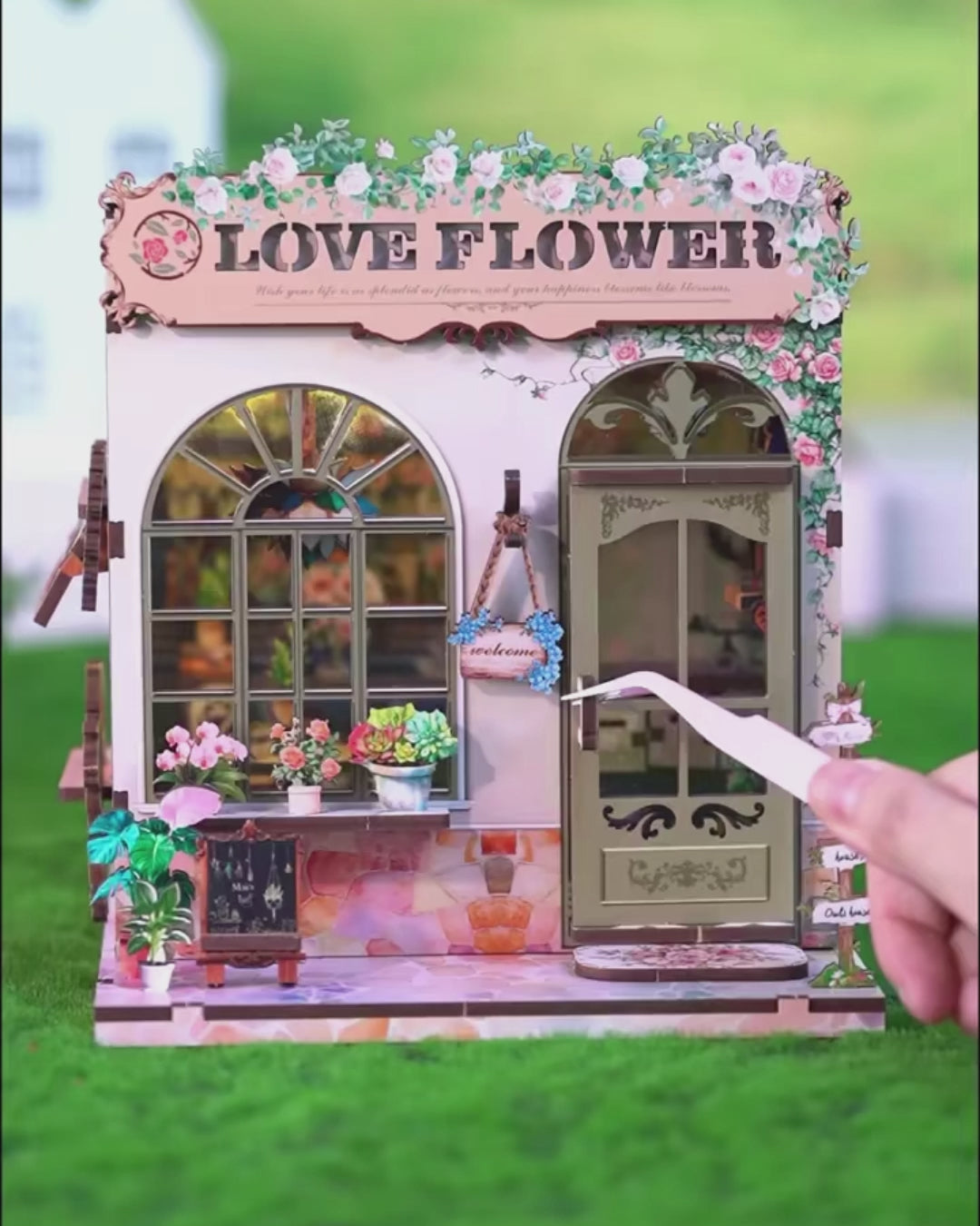 DIY book nook kit “Maison de Fleurs,” featuring a pastel-toned miniature flower shop with arched windows, blooming plants, stone accents, and romantic signage. A relaxing DIY and crafts project for fans of tiny dollhouses and garden-inspired scenes.